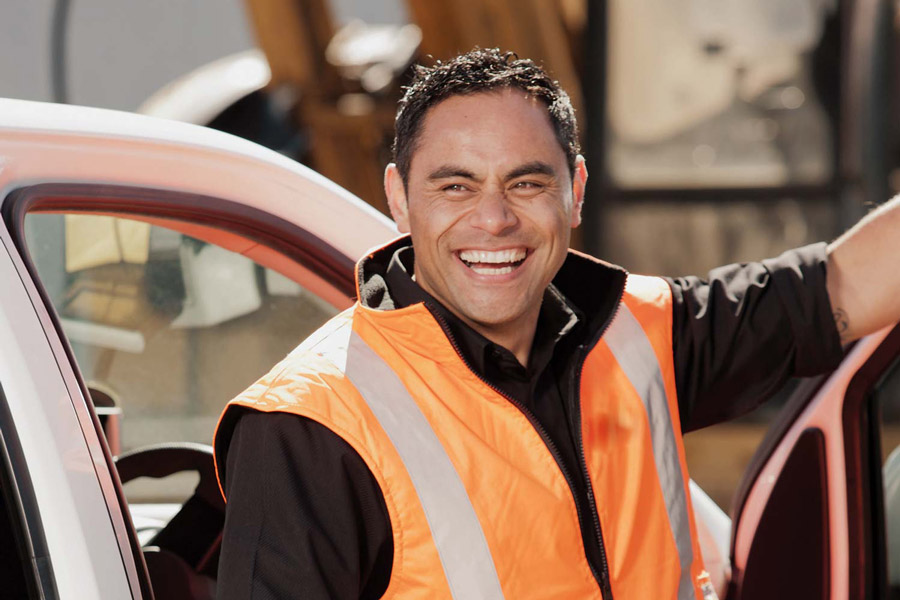 Photo of a smiling construction worker wearing a bright orange high-vis vest