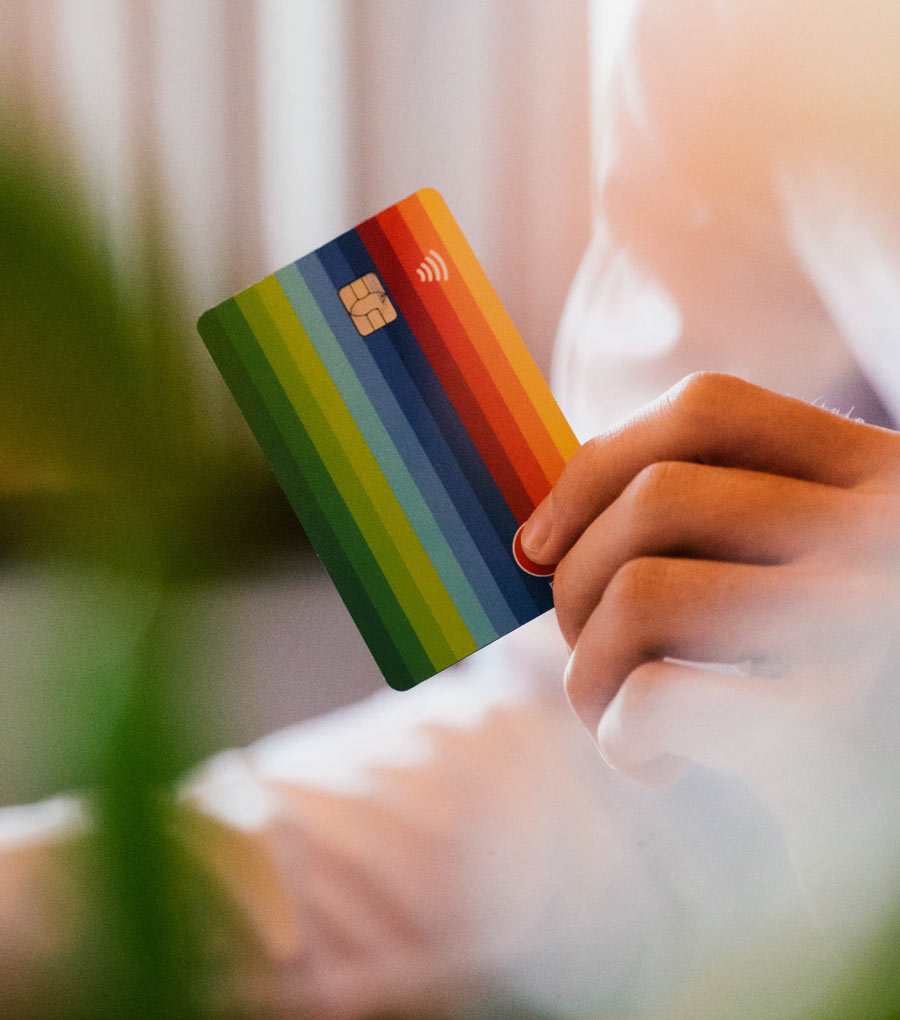 Photo of a hand holding a credit card with a rainbow stripes design