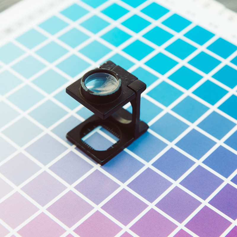 Photo of a magnifying glass sitting atop a Pantone swatch chart