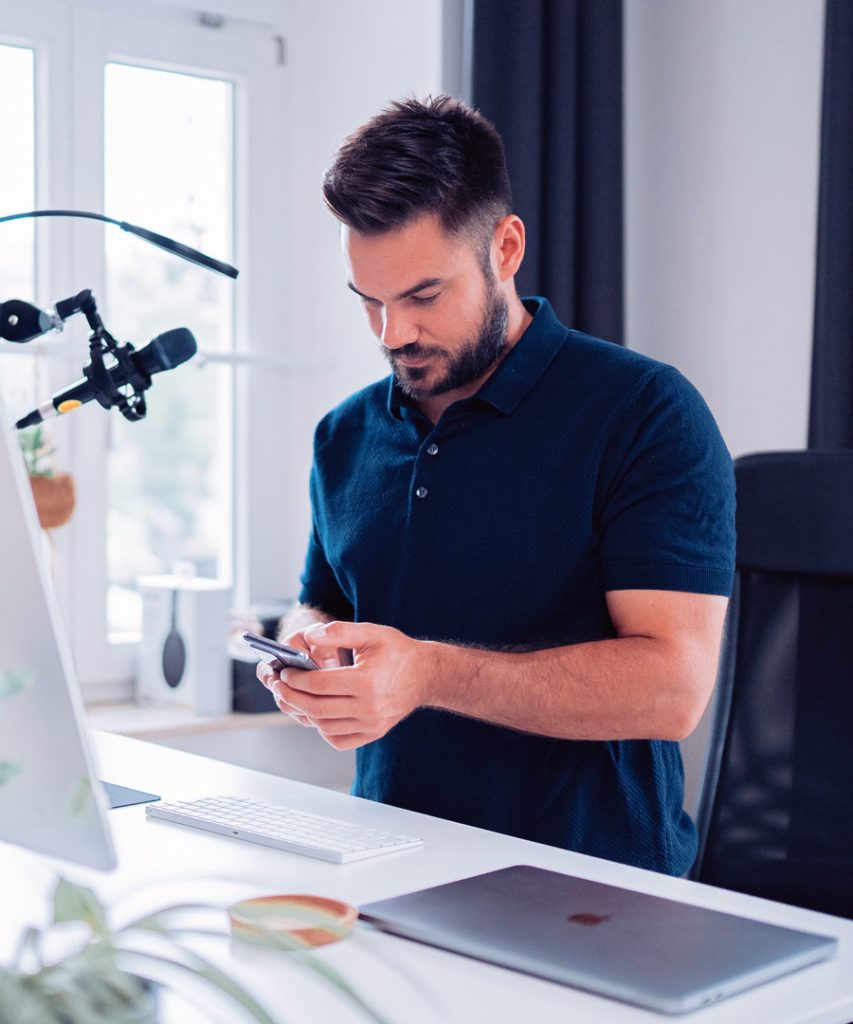 Photo of a young person using their smartphone, standing at a desk